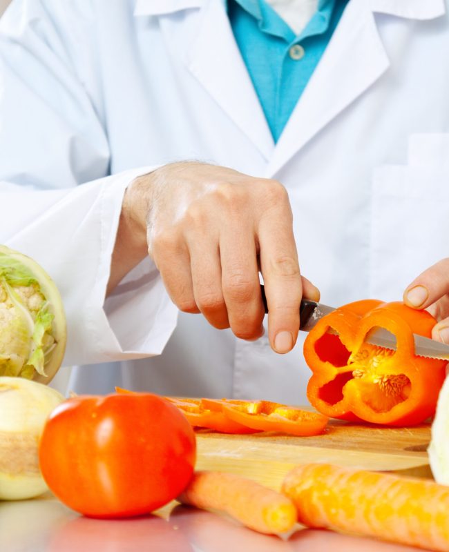 Close up shop of hands cuts vegetables on cutting board